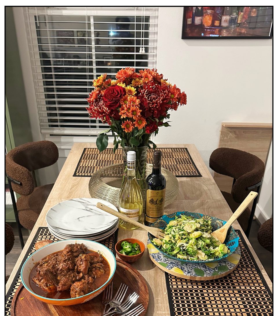 Lime & Dine Sunday table with stew chicken, flowers, and wine